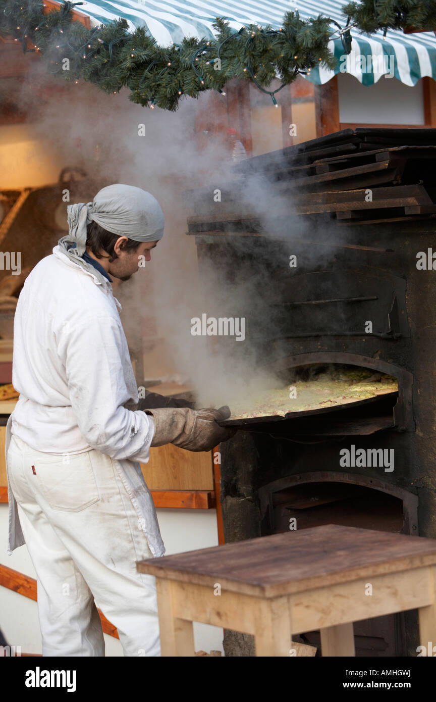 Baker rimozione del vassoio del pane da un esterno in legno forno di cottura su una fase di stallo con fuoriuscita di vapore al mercato di Natale Berlino Foto Stock