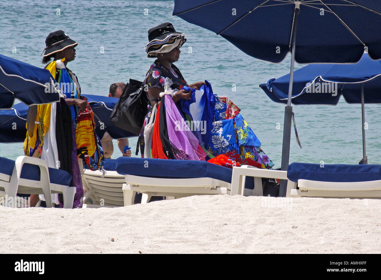 Le donne la vendita di cappelli e asciugamani da spiaggia a piedi tra lettini grande spiaggia della Baia di Philipsburg St Maarten Foto Stock