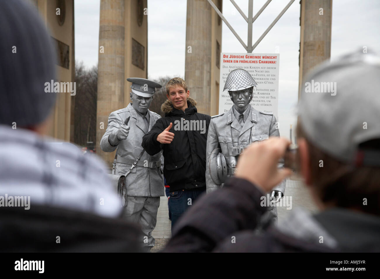 Turista che posano per una fotografia con verniciato argento street intrattenitore vestito come est guardia tedesco Porta di Brandeburgo a Berlino Foto Stock