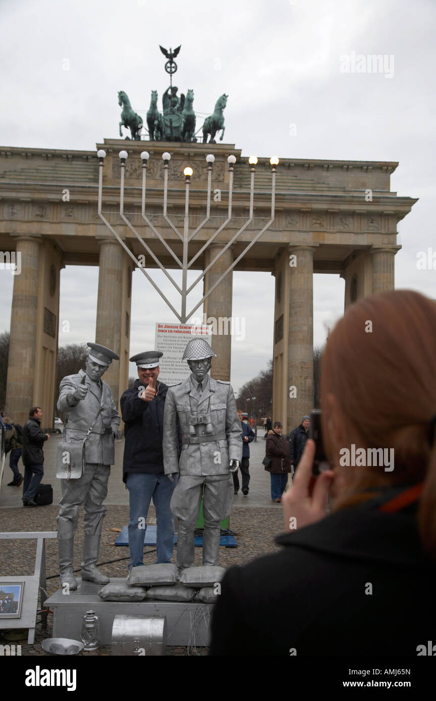 Turista che posano per una fotografia con verniciato argento street intrattenitore vestito come est guardia tedesco Porta di Brandeburgo a Berlino Foto Stock