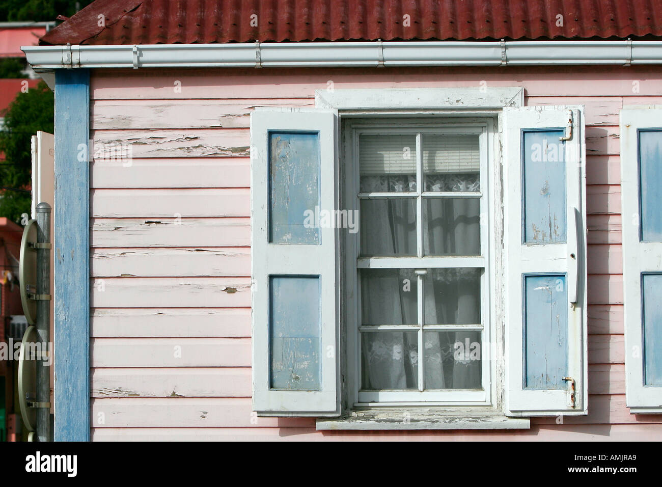 Peeling di resistenza agli agenti atmosferici di vernice rosa sulla casa con persiane Gustavia St Barts Foto Stock