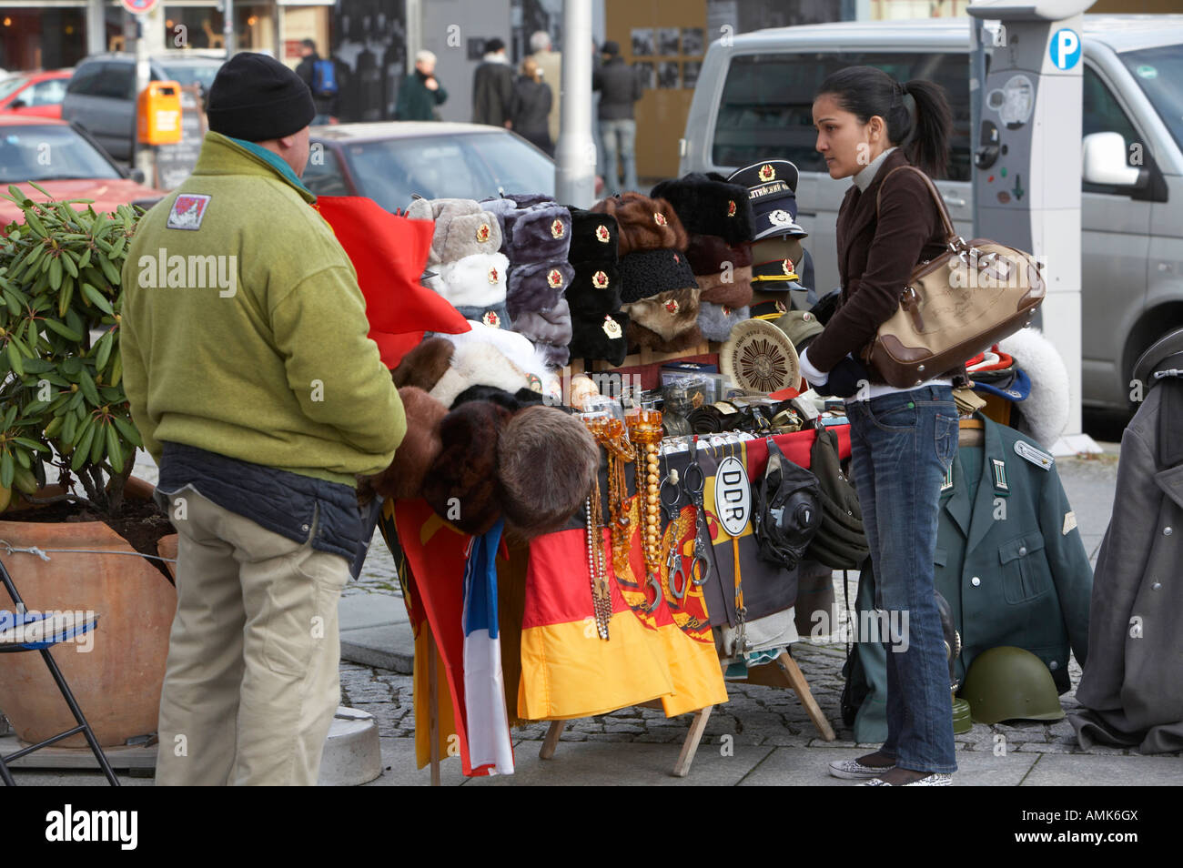 Turista femminile esamina oriente russo e tedesco memorabilia in vendita su una bancarella di strada nelle vicinanze del Checkpoint Charlie Berlino Germania Foto Stock