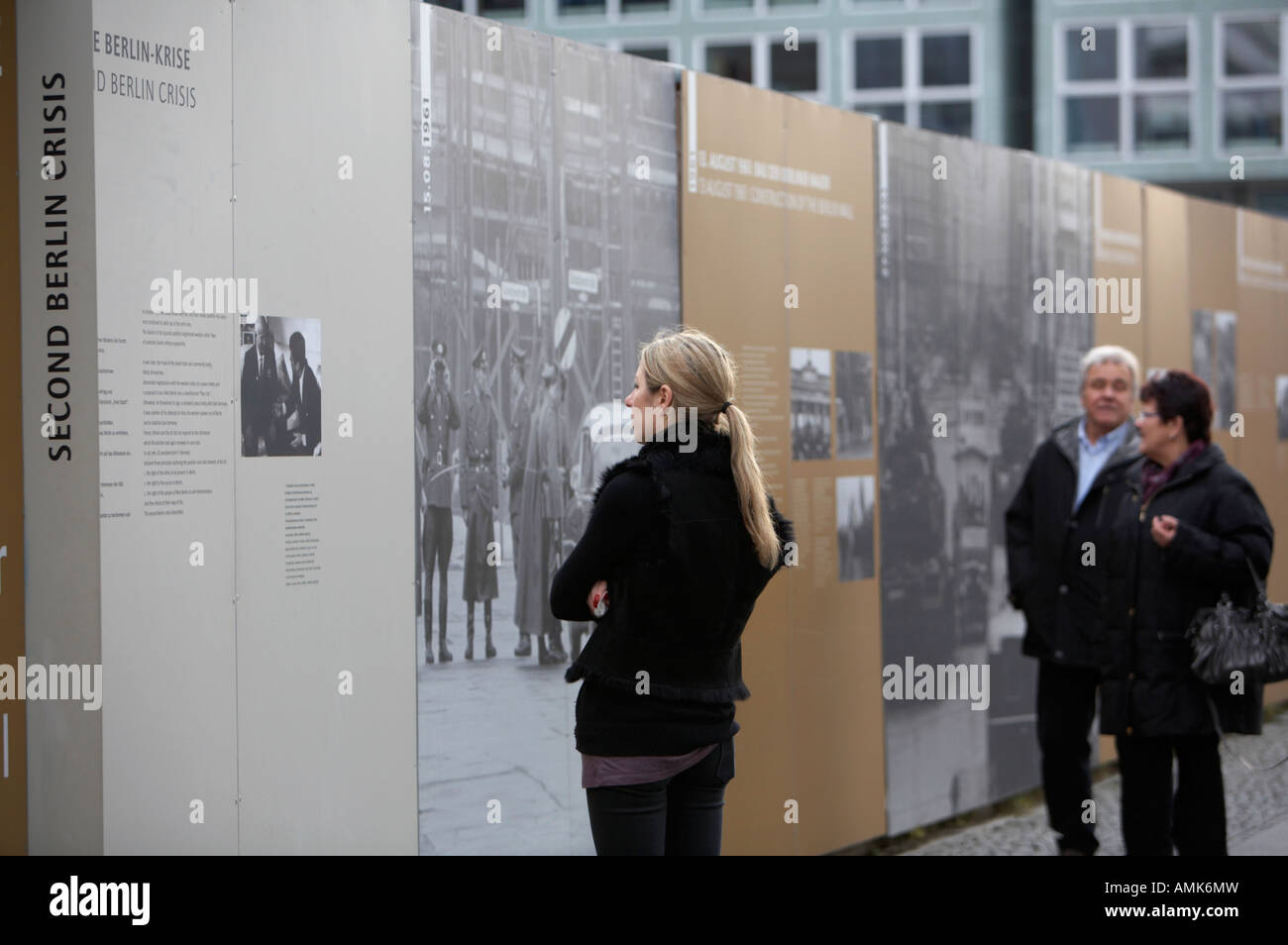 Turista femminile legge la storia del muro di Berlino e la crisi al Checkpoint Charlie Berlino Germania Foto Stock