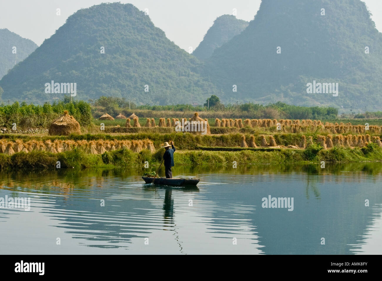 L'agricoltore cinese su una zattera di bamboo in Li Jiang fiume pietre calcaree carsiche Yangshuo Cina provincia di Guangxi Foto Stock