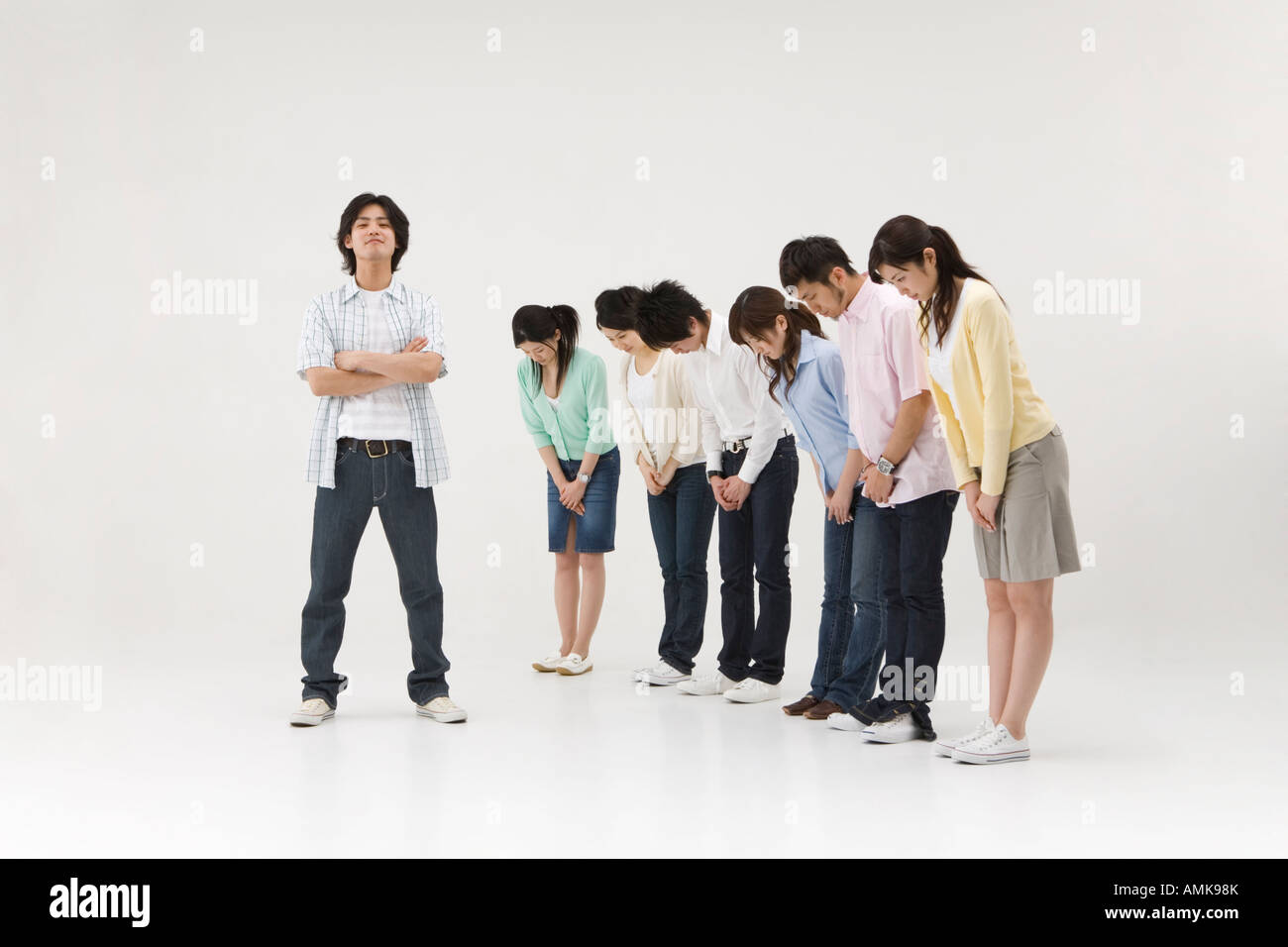Gruppo di persone che si inchinano a un giovane uomo Foto Stock