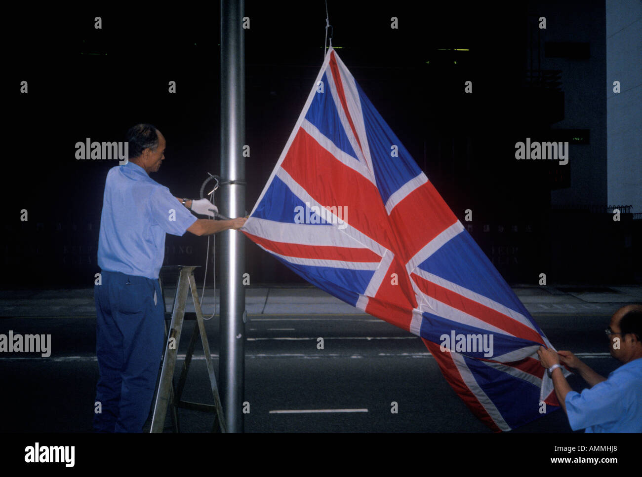 L'uomo abbassando britannica Union Jack flag in Hong Kong Foto Stock