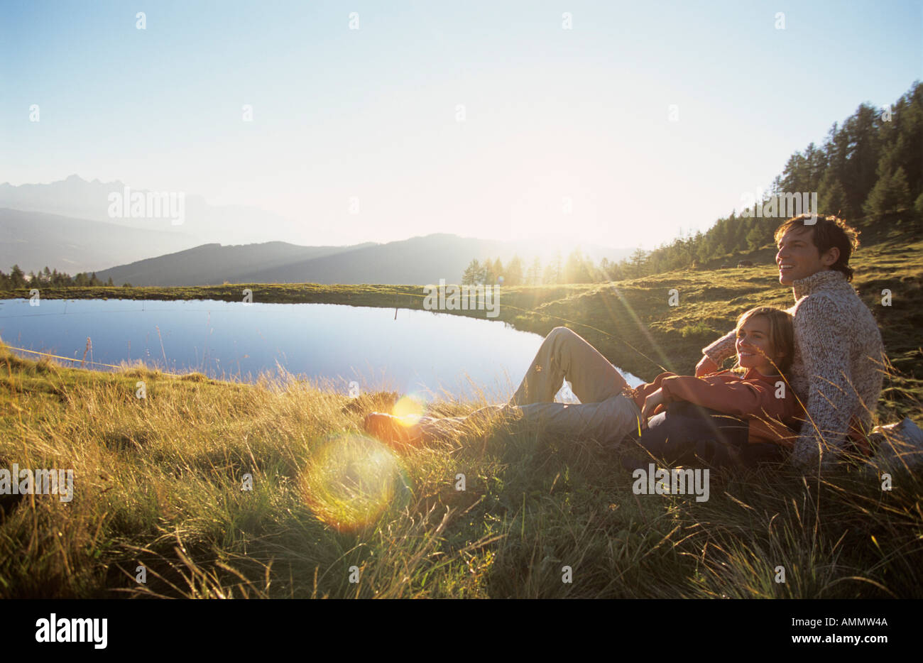 Giovane seduto sul prato all'alba Foto Stock