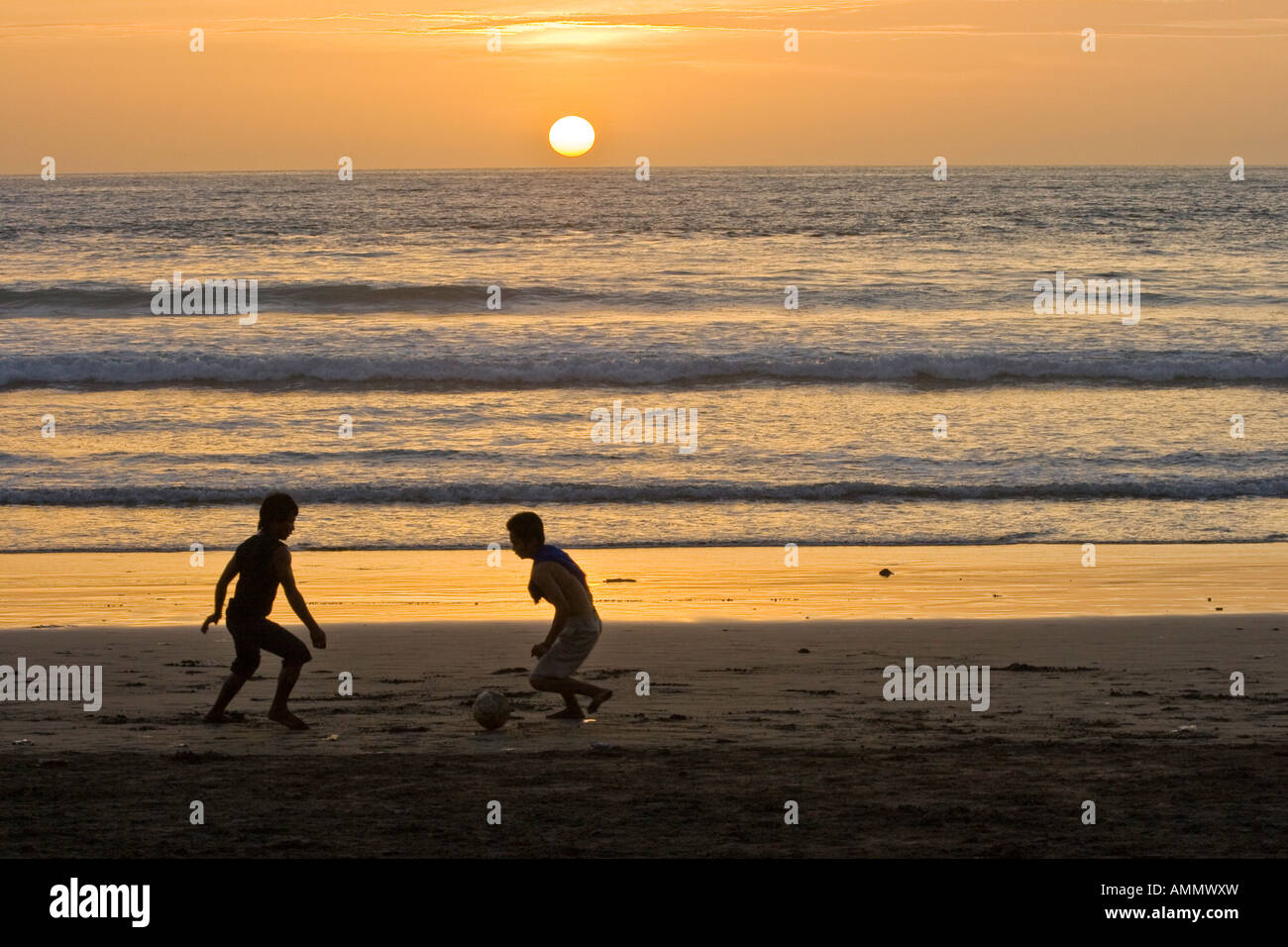 Ragazzi indonesiani a giocare a calcio al tramonto sulla spiaggia di Kuta Bali Indonesia Foto Stock