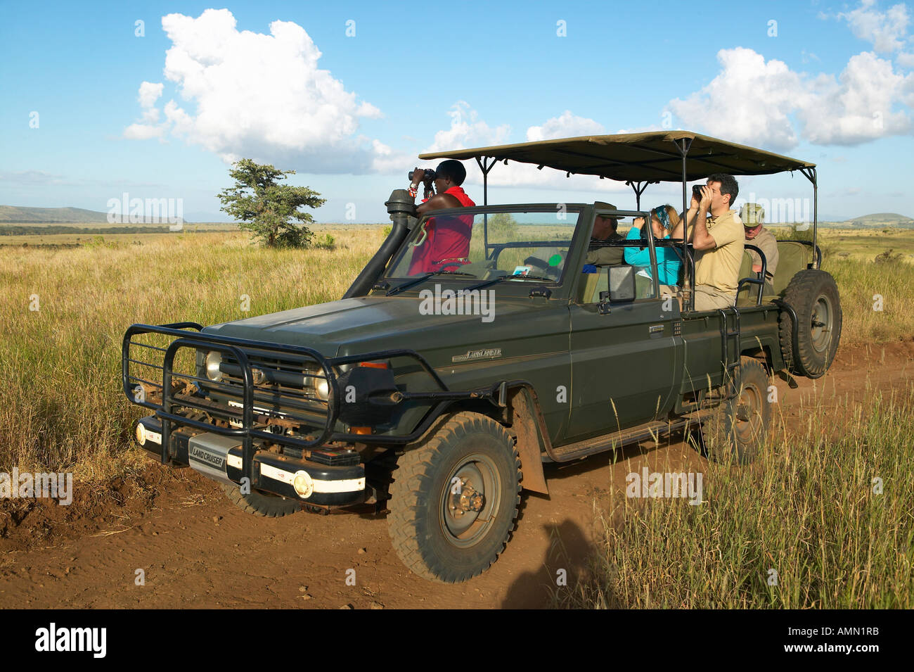 Landrover e gruppo di Safari alla ricerca di animali in Masai Mara vicino a poco governatore s camp Kenya Africa Foto Stock