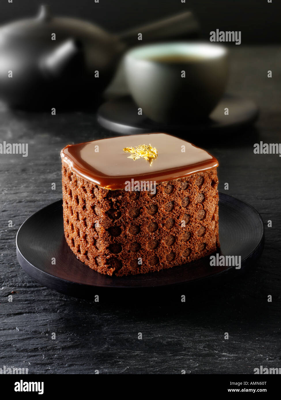 Una specialità di pasticceria fatta a mano ricca torta di cioccolato indulgente ripiena di caffè in un tavolo nero Foto Stock