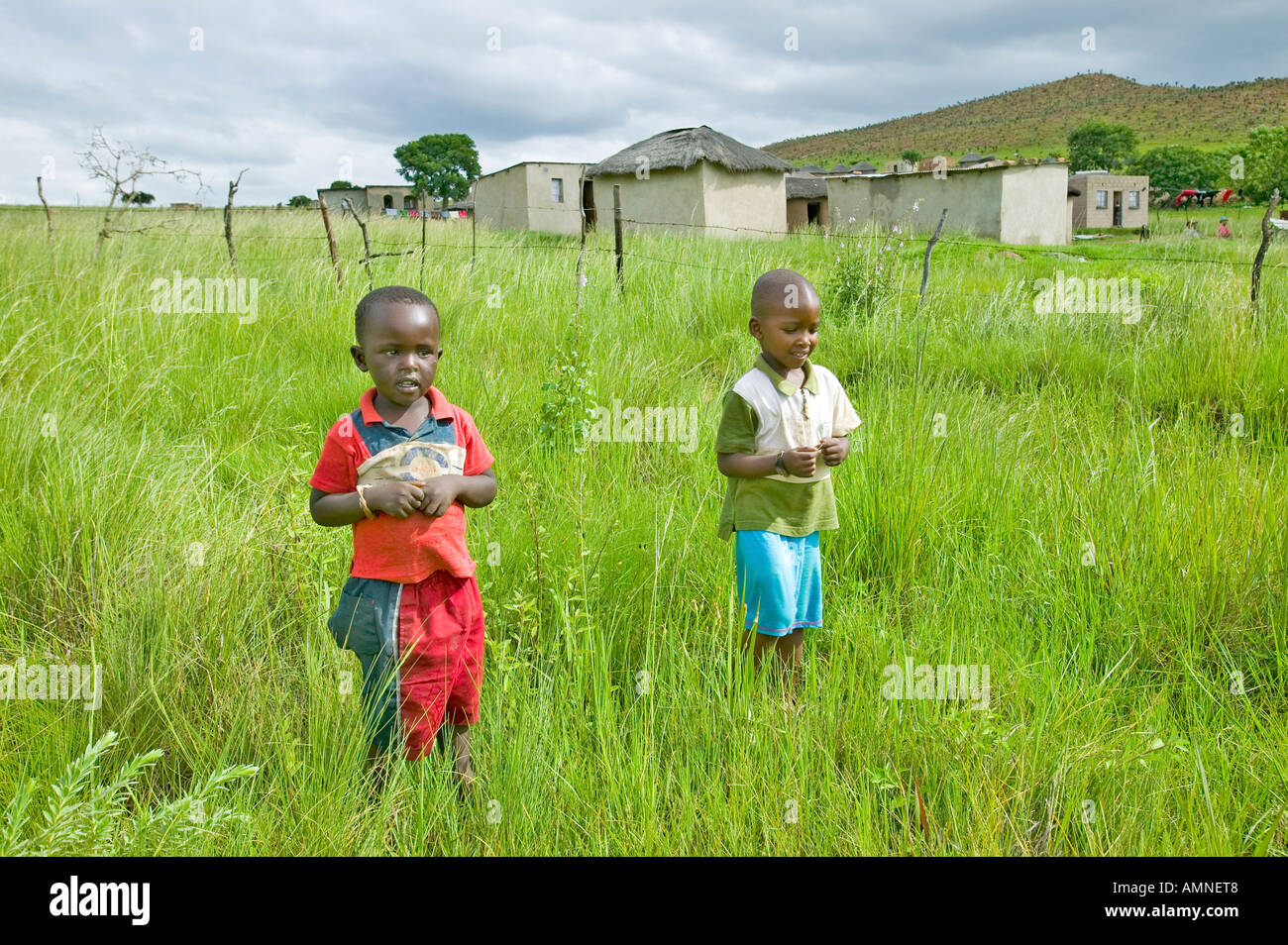 Due Zulu ragazzi nero nella zona rurale di Zululand con il villaggio di sfondo in Sud Africa Foto Stock