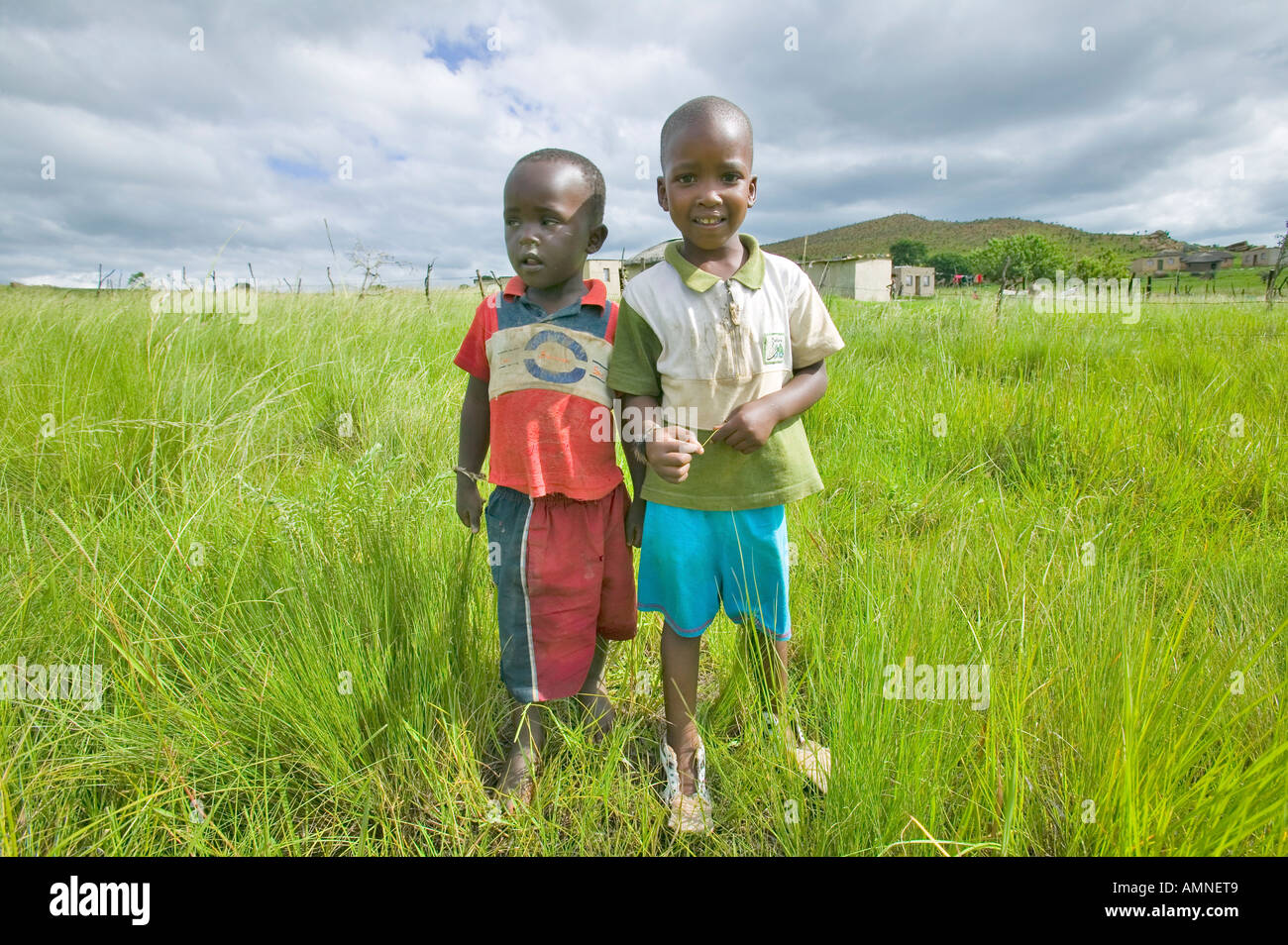 Due Zulu ragazzi nero nella zona rurale di Zululand con il villaggio di sfondo in Sud Africa Foto Stock
