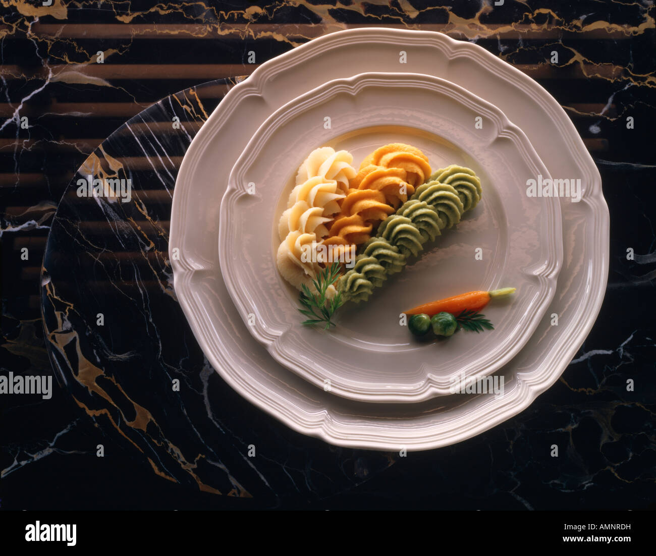 Il segnale di PEA Carrott patate purea di verdure su una piastra bianca sul marmo nero. La Nouvelle cuisine piatto vegetariano. Foto Stock