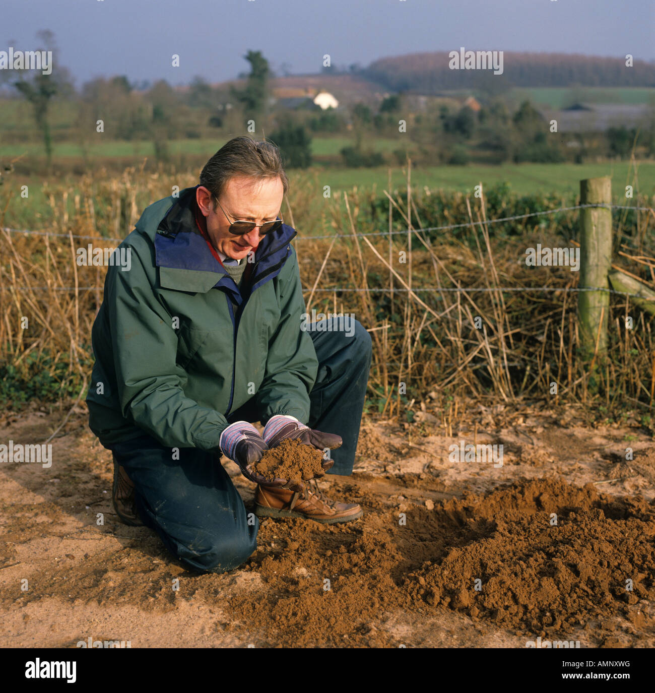 Agricoltore esaminando terreno di argilla sabbiosa nelle sue mani Devon Foto Stock