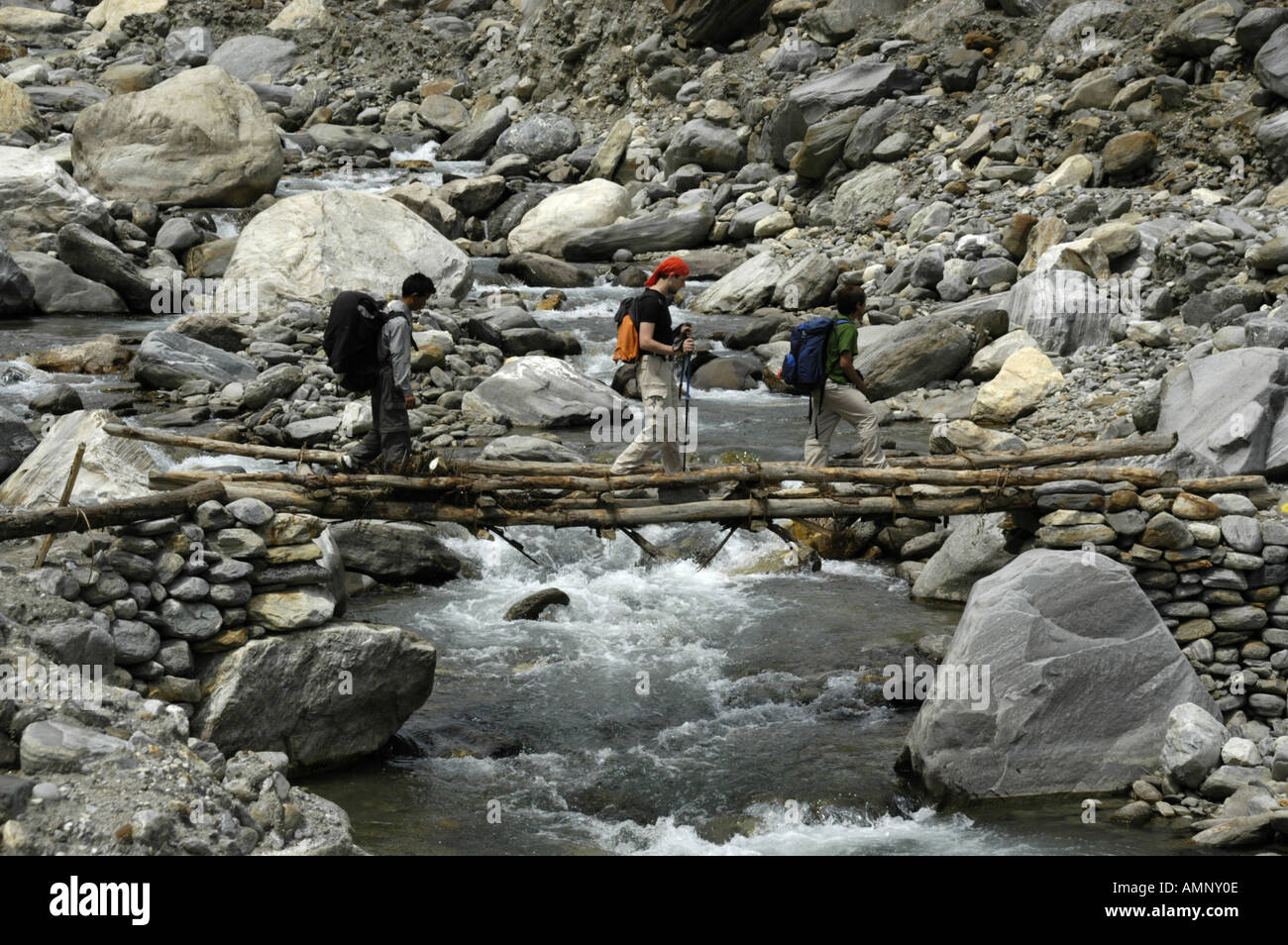 Le persone che attraversano un semplice ponte sopra un torrente di montagna Regione Annapurna Nepal Foto Stock
