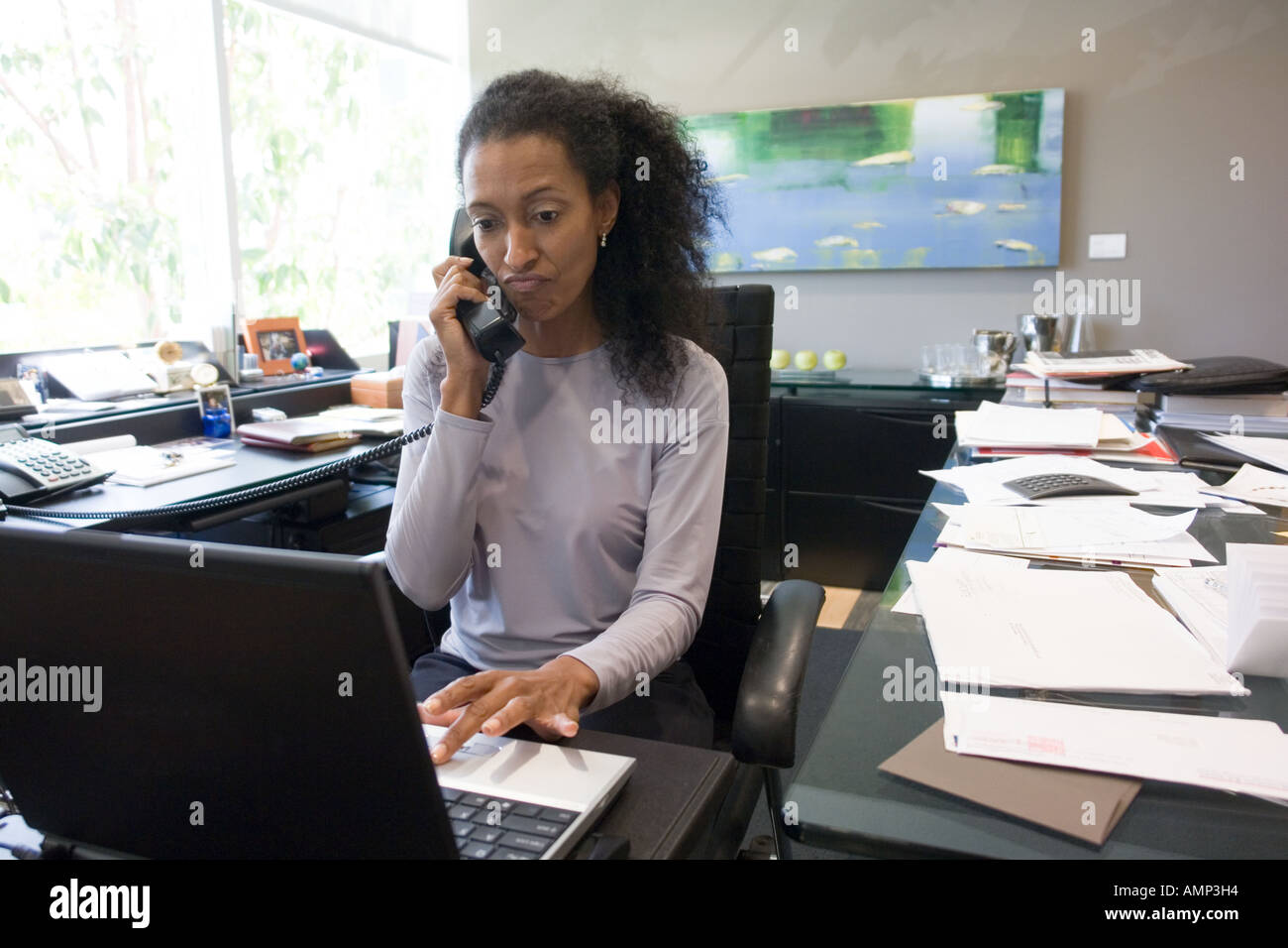 Business donna parlare al telefono e digitare sul computer portatile Foto Stock