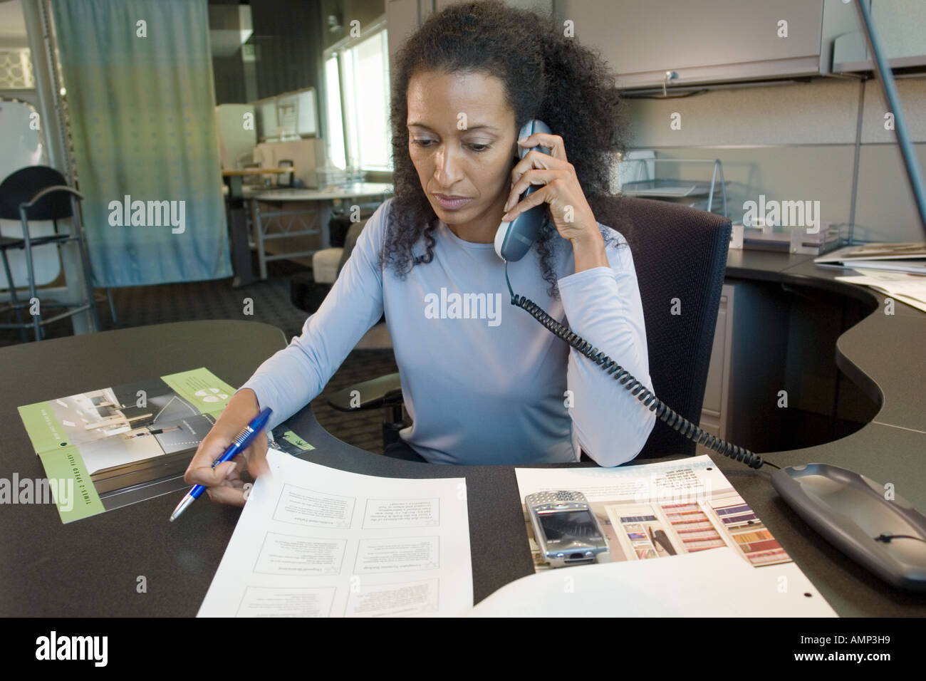 Seduto business donna utilizzando il telefono desk Foto Stock