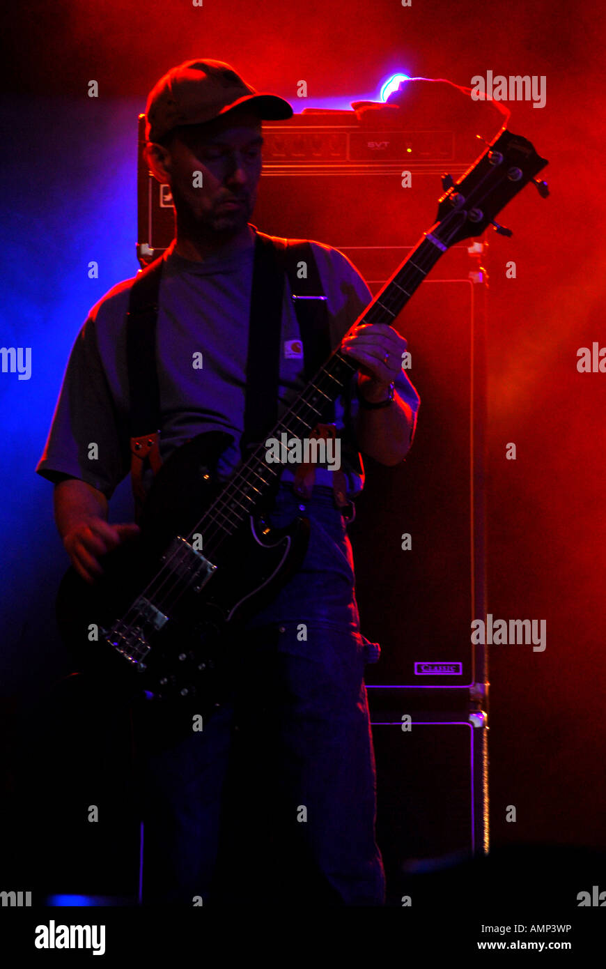 Il bassista dalla sezionatrice medici in berretto da baseball esibirsi sul palco con blu e retroilluminazione rossa Wychwood Festival 2006 Foto Stock