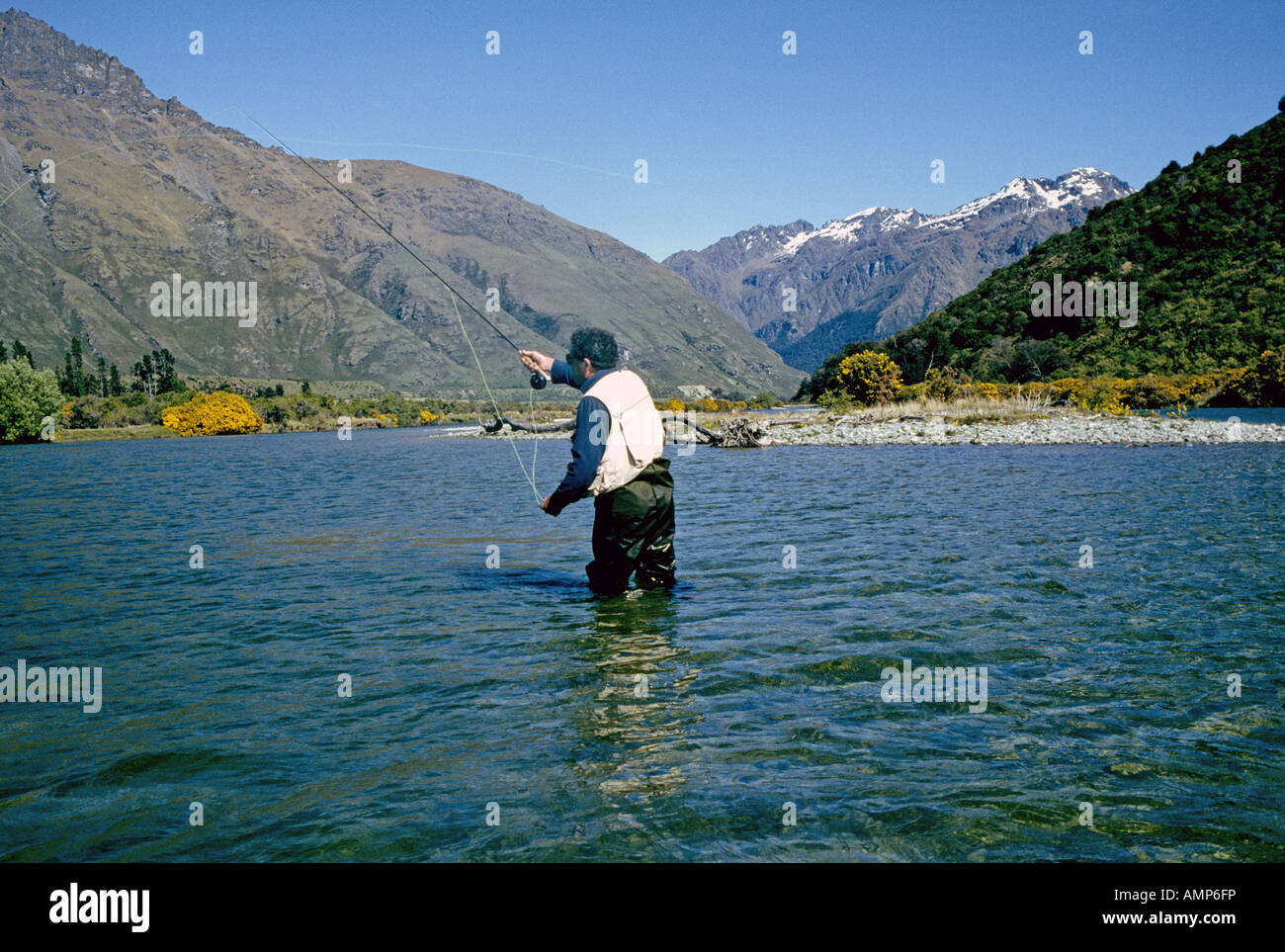 Nuova Zelanda Isola del Sud un pescatore a mosca cast per grandi imprese tedesche trota marrone in un lago di montagna in straordinarie montagne Foto Stock