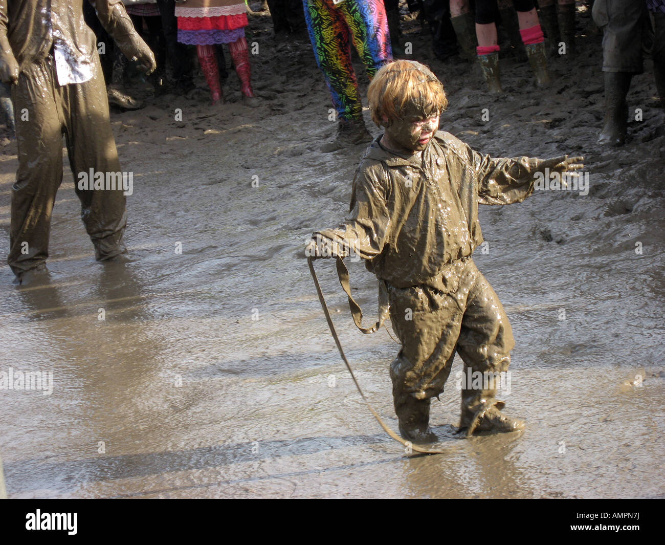 Ragazzo giovane completamente coperti di fango a giocare in grandi pozza di fango a Glastonbury 2007 Foto Stock
