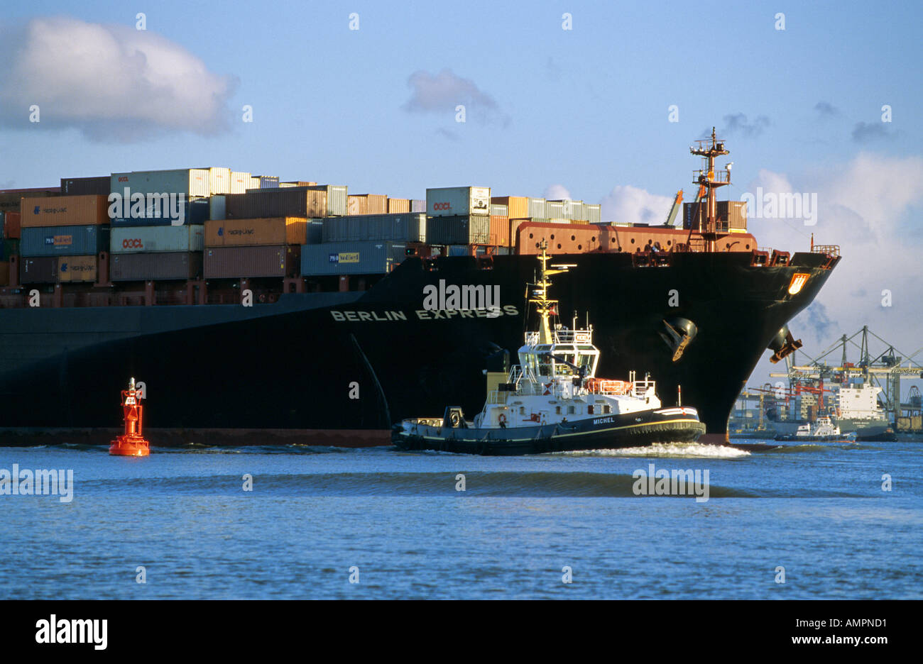 Rimorchiatore scortando un enorme contenitore nave sul fiume Elba a Amburgo Germania Foto Stock