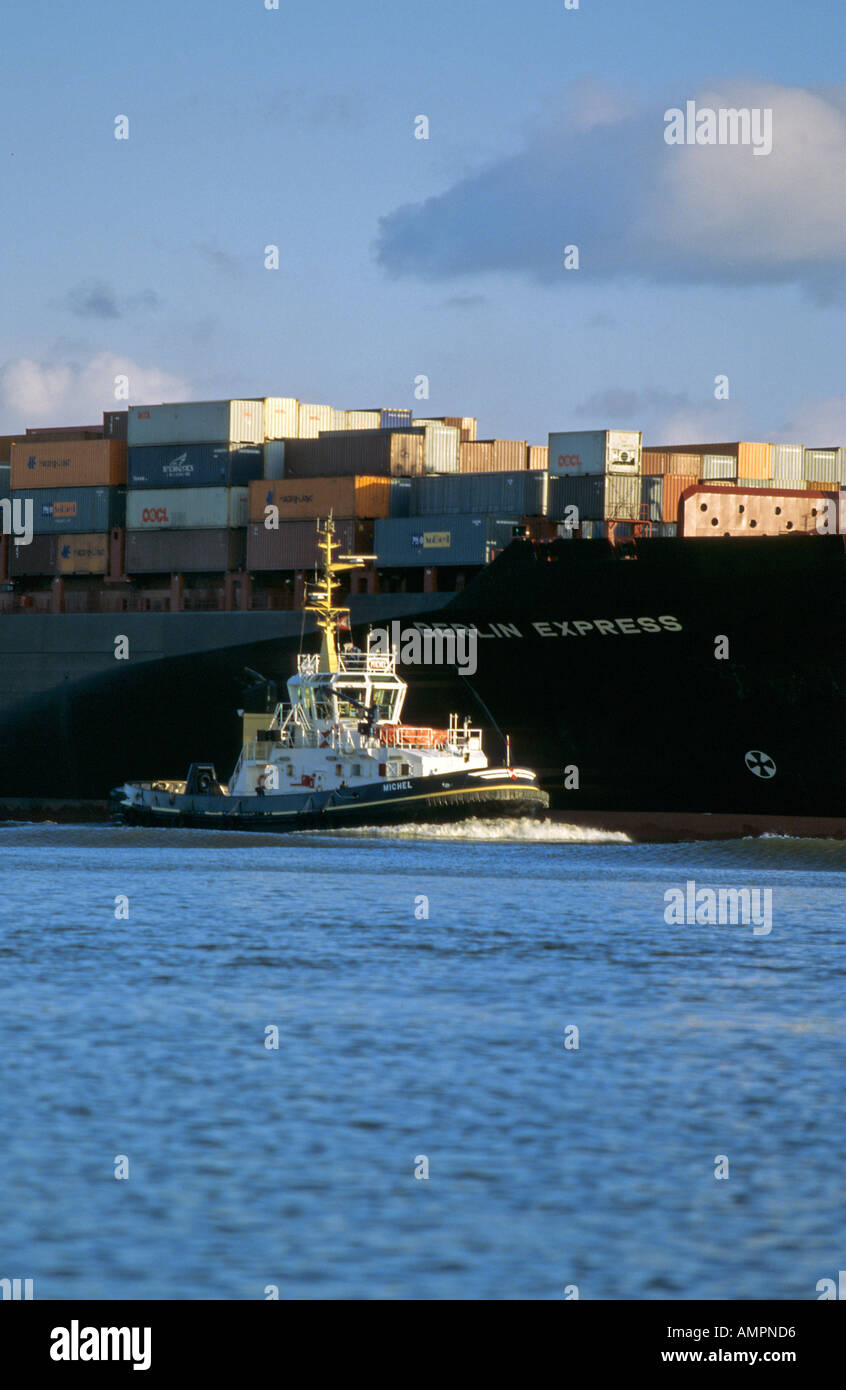Rimorchiatore scortando un enorme contenitore nave sul fiume Elba a Amburgo Germania Foto Stock