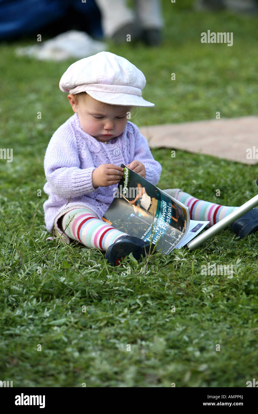 Il Toddler indossando colorato vestito e cappuccio a maglia seduto sull'erba Foto Stock
