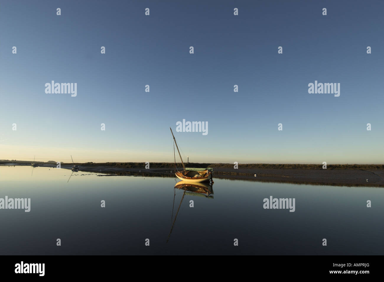 Barca nelle zone costiere creek al crepuscolo Brancaster Norfolk Inghilterra Dicembre Foto Stock