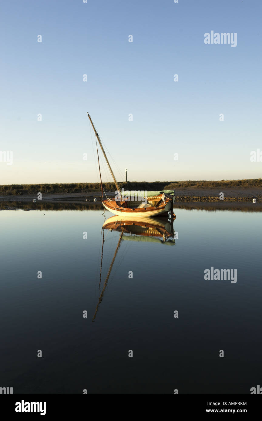 Barca nelle zone costiere creek al crepuscolo Brancaster Norfolk Inghilterra Dicembre Foto Stock