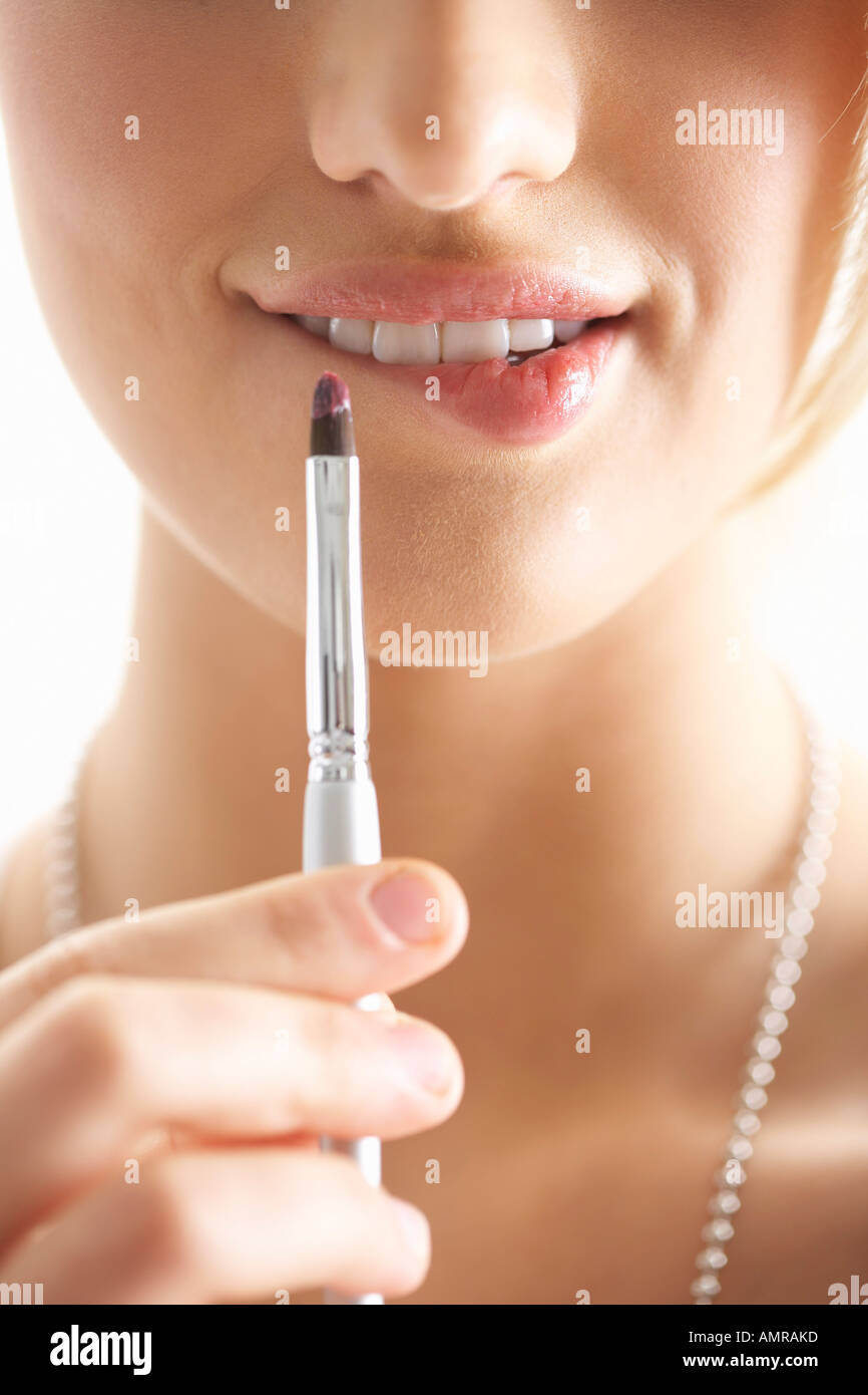 Ragazza di mordere le labbra e tenendo il rossetto Foto stock - Alamy