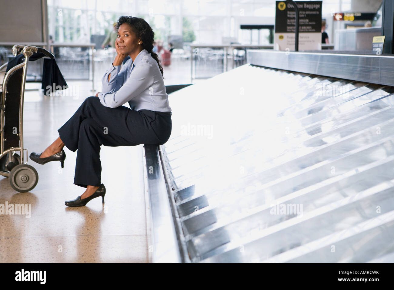 Donna africana in attesa in aeroporto il reclamo bagagli Foto Stock