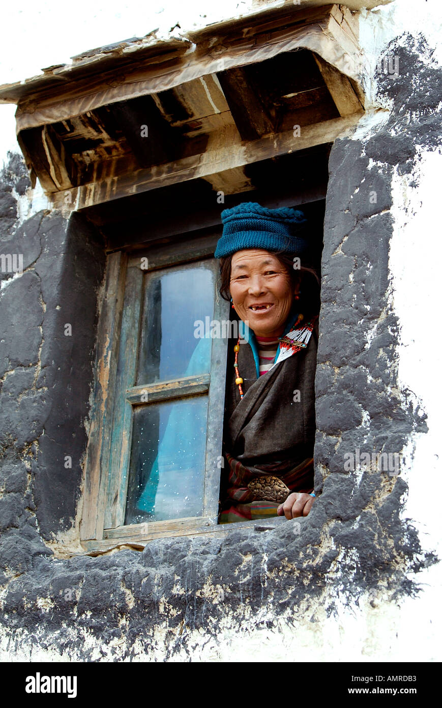 Donna sorridente con denti mancanti si affaccia dalla tradizionale tibetana di finestra con cornice nera Foto Stock
