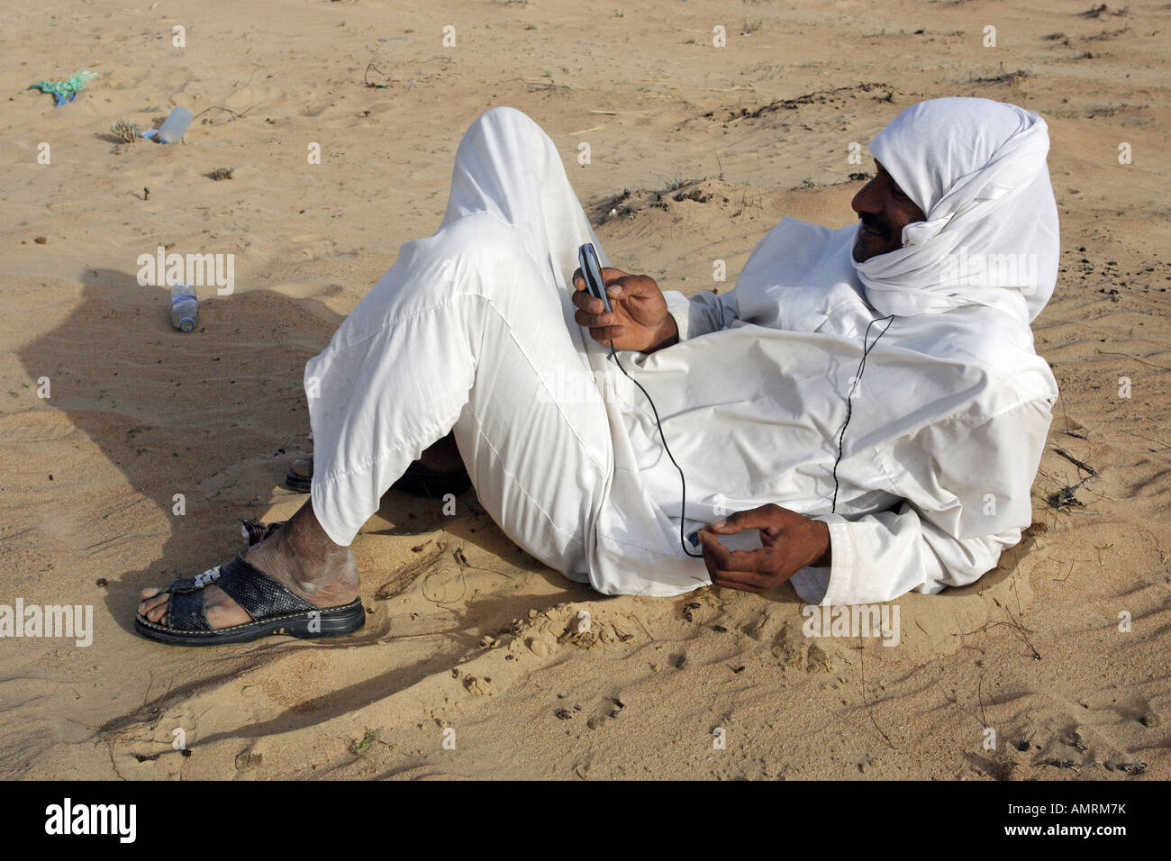 L'uomo nel deserto, utilizzando il suo telefono cellulare, Dubai, Emirati Arabi Uniti Foto Stock