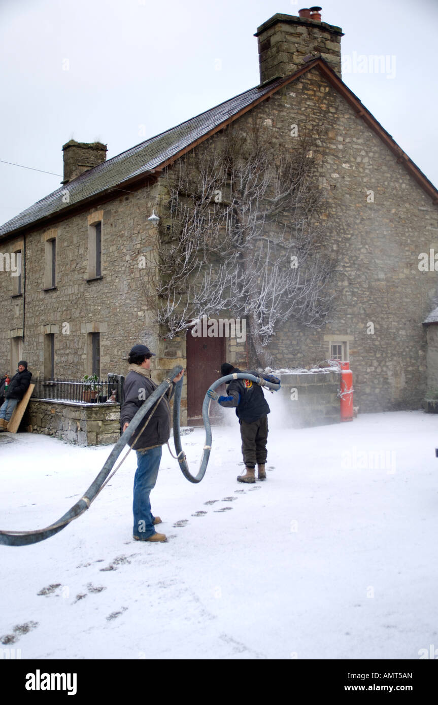 SNOW BUSINESS due uomini fake spruzzo neve artificiale sul cantiere di fattoria per far sembrare invernale per la registrazione di film programma televisivo Foto Stock