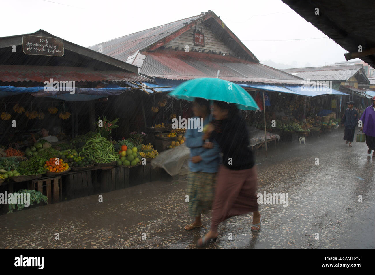 Myanmar Stato Shan Kalaw mercato giornaliero sotto pesanti piogge monsoniche vista con due donne a piedi da sotto ombrellone Foto Stock