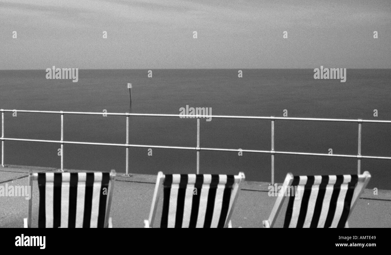 Sedie a sdraio sulla passeggiata lungomare di Teignmouth al crepuscolo Foto Stock