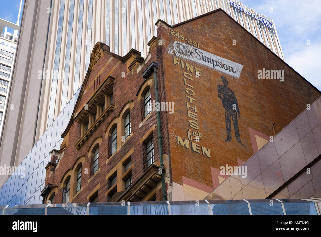 Vecchio annuncio, sul lato di un edificio in mattoni. In contrasto, un moderno hotel sorge alle spalle. Foto Stock