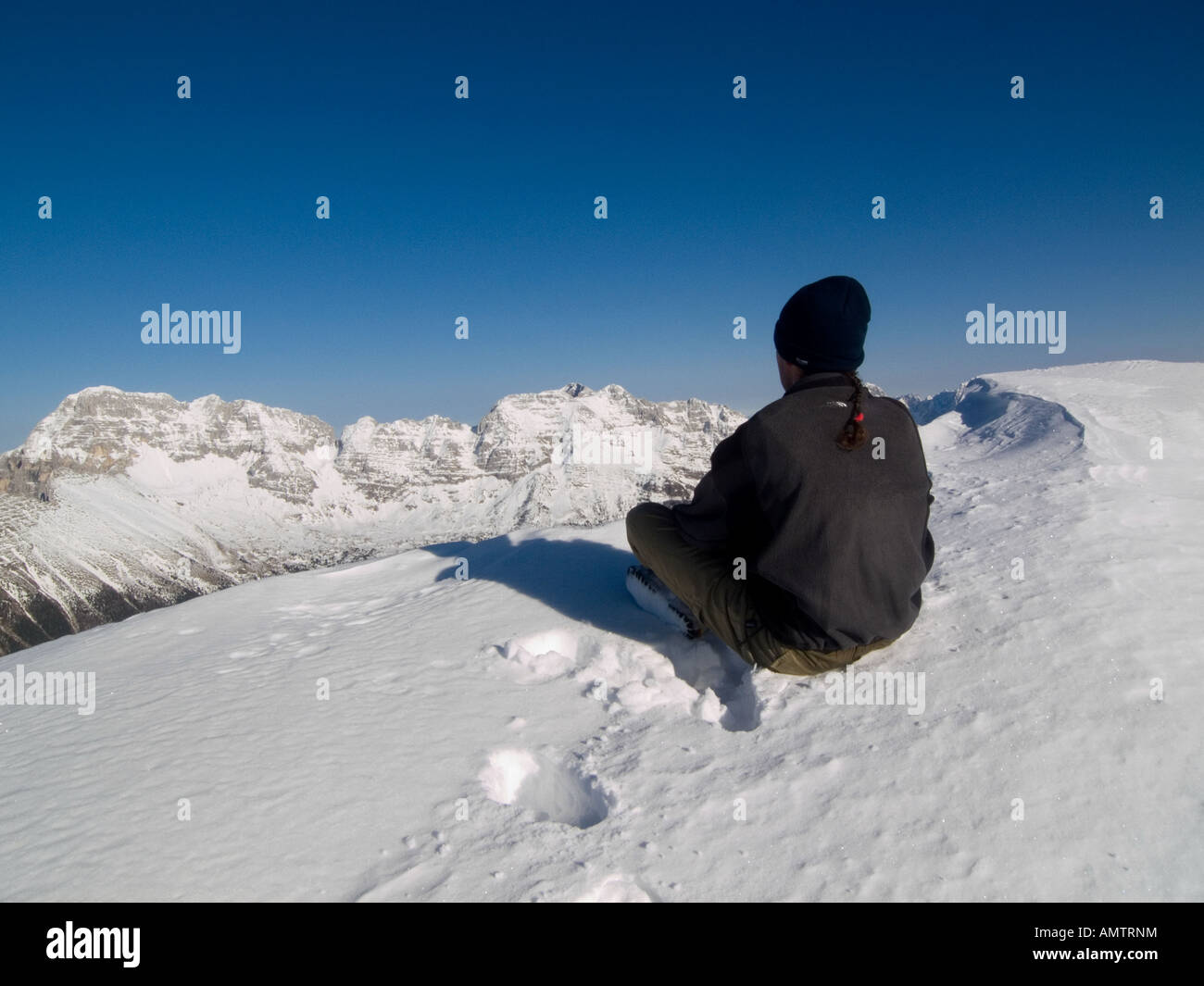 Uomo seduto nella neve e guardare l'orizzonte in Alpi Giulie Sart Montagna Italia Foto Stock