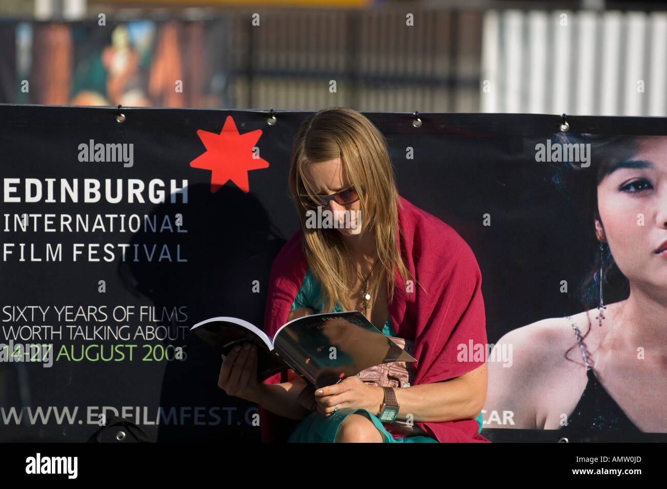 Donna di lettura da una pubblicità tramite Affissioni Edinburgh International Film Festival Foto Stock
