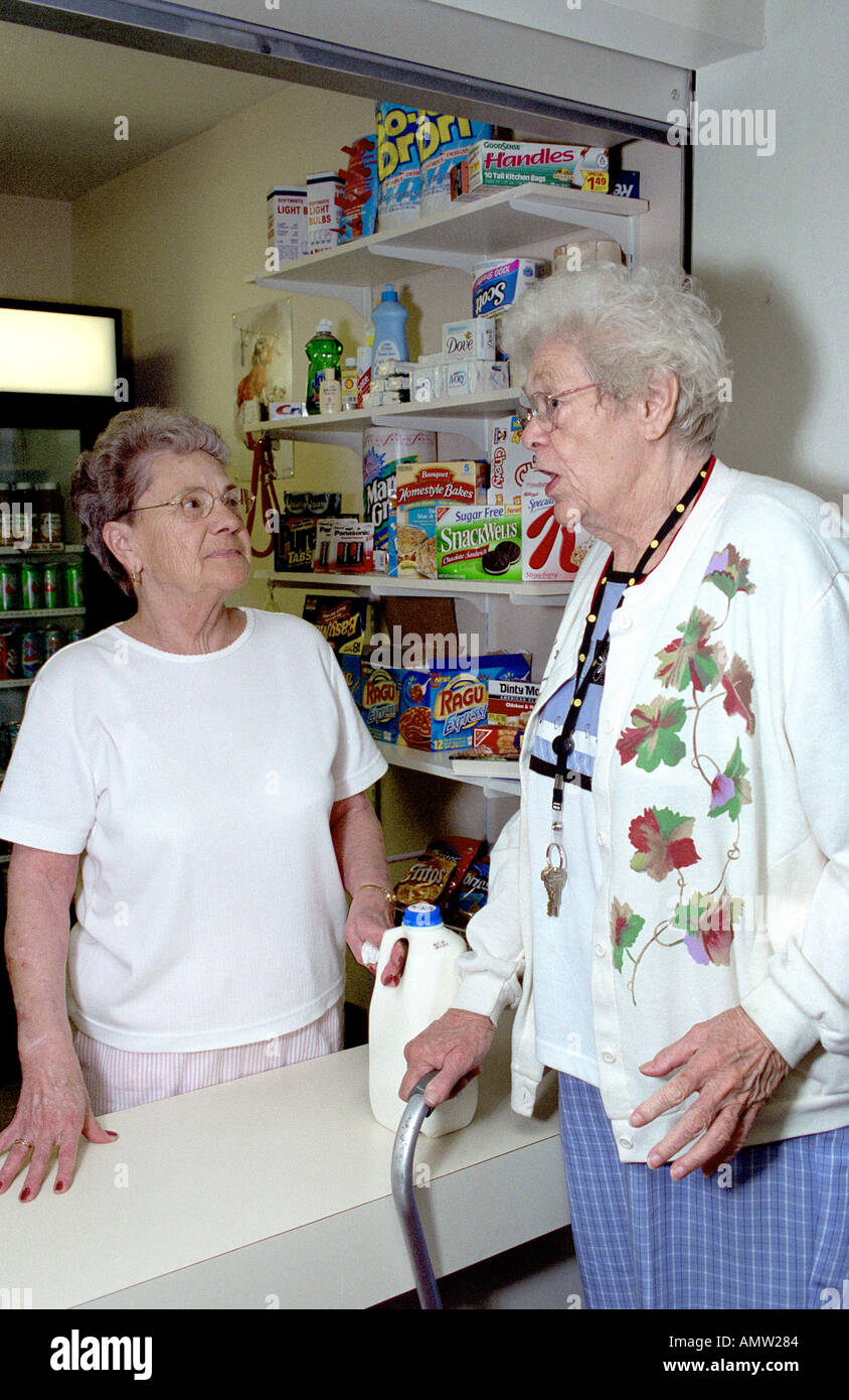 2 senior femmine hanno la conversazione su un negozio all'interno di un complesso di senior Foto Stock