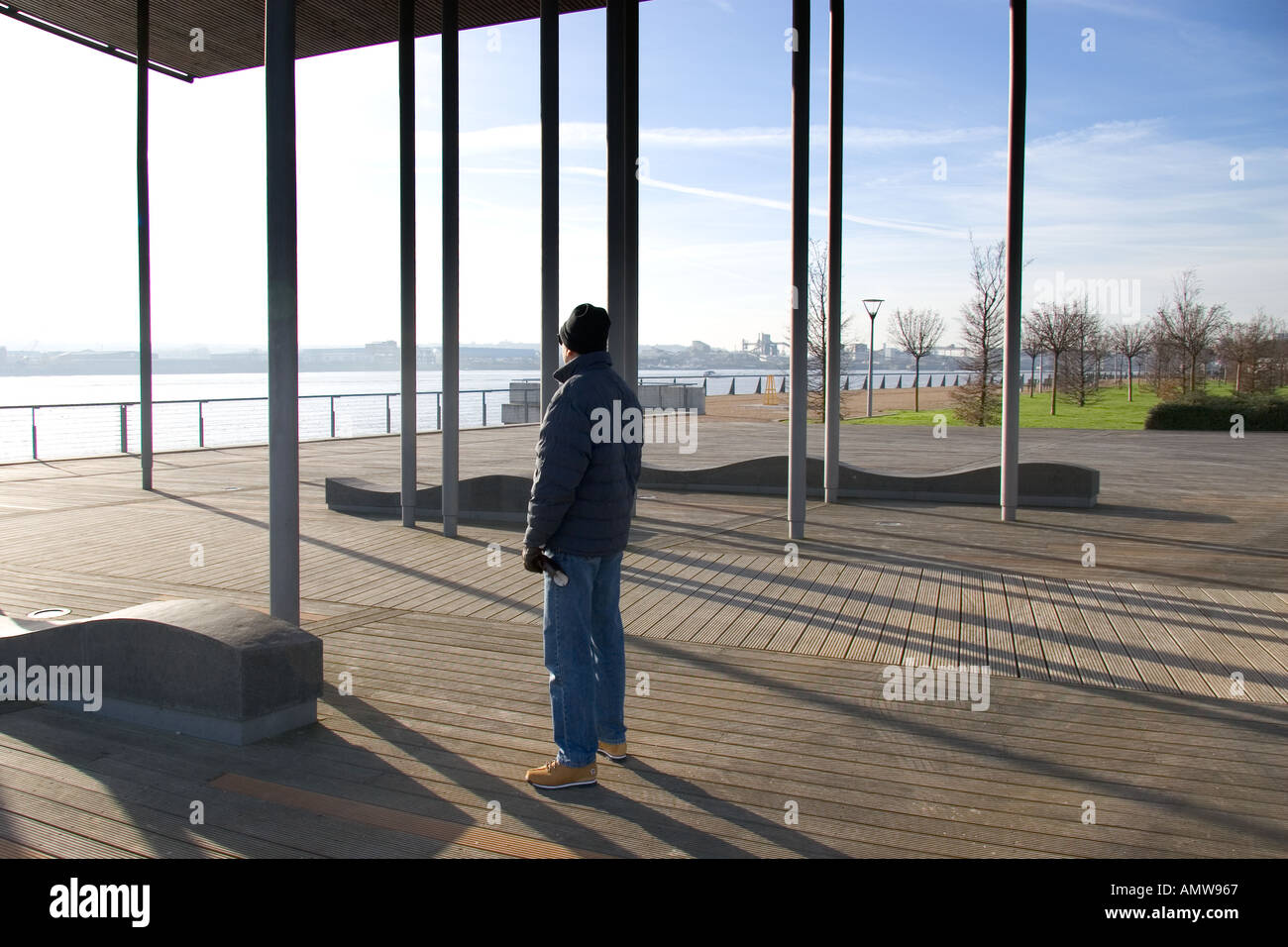 Uomo in piedi su decking cercando in una giornata di sole con appartamento edificio in background Modello rilasciato Foto Stock