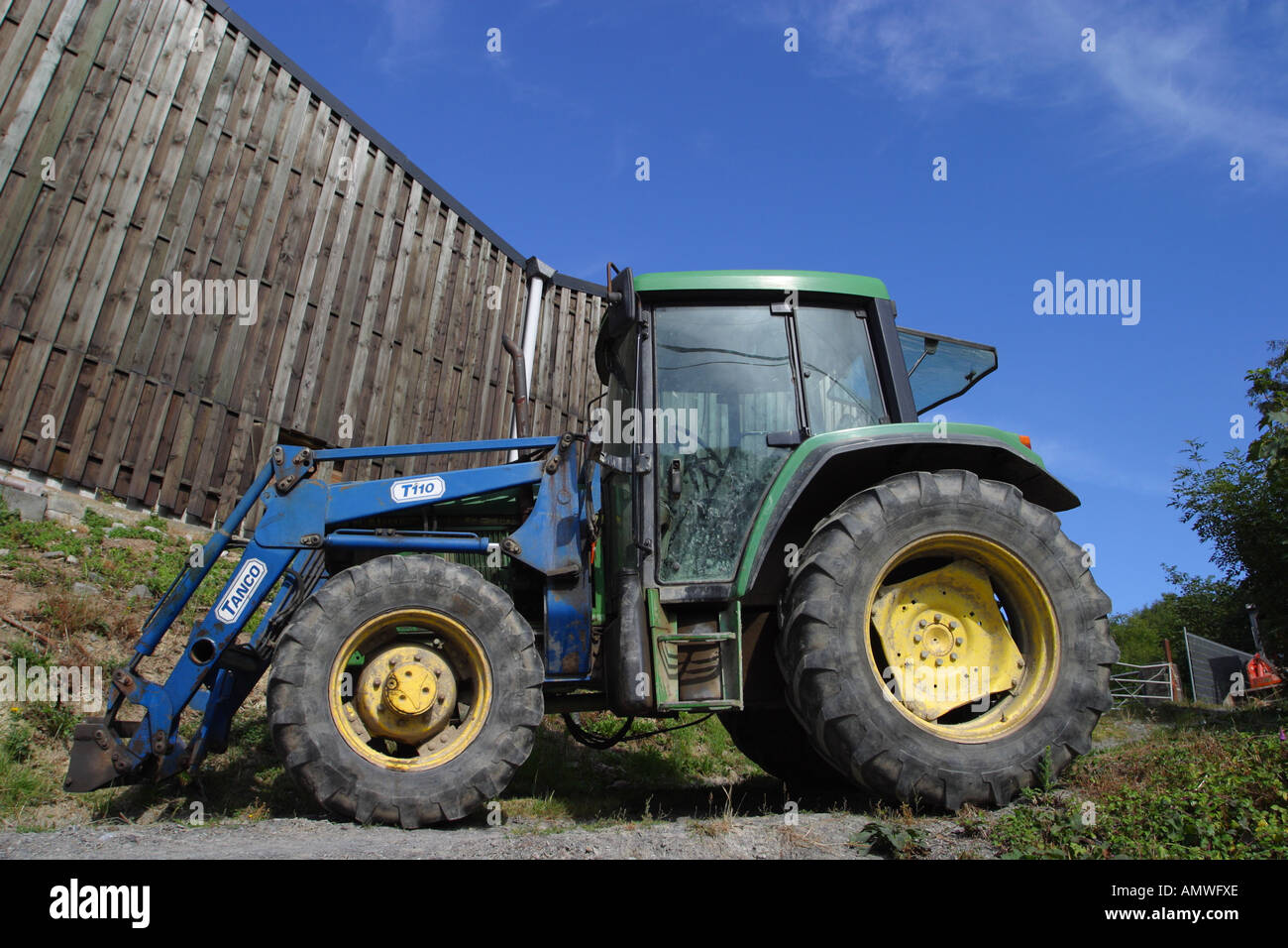 Trattore agricolo veicolo con summer blue sky a fianco di un granaio Foto Stock