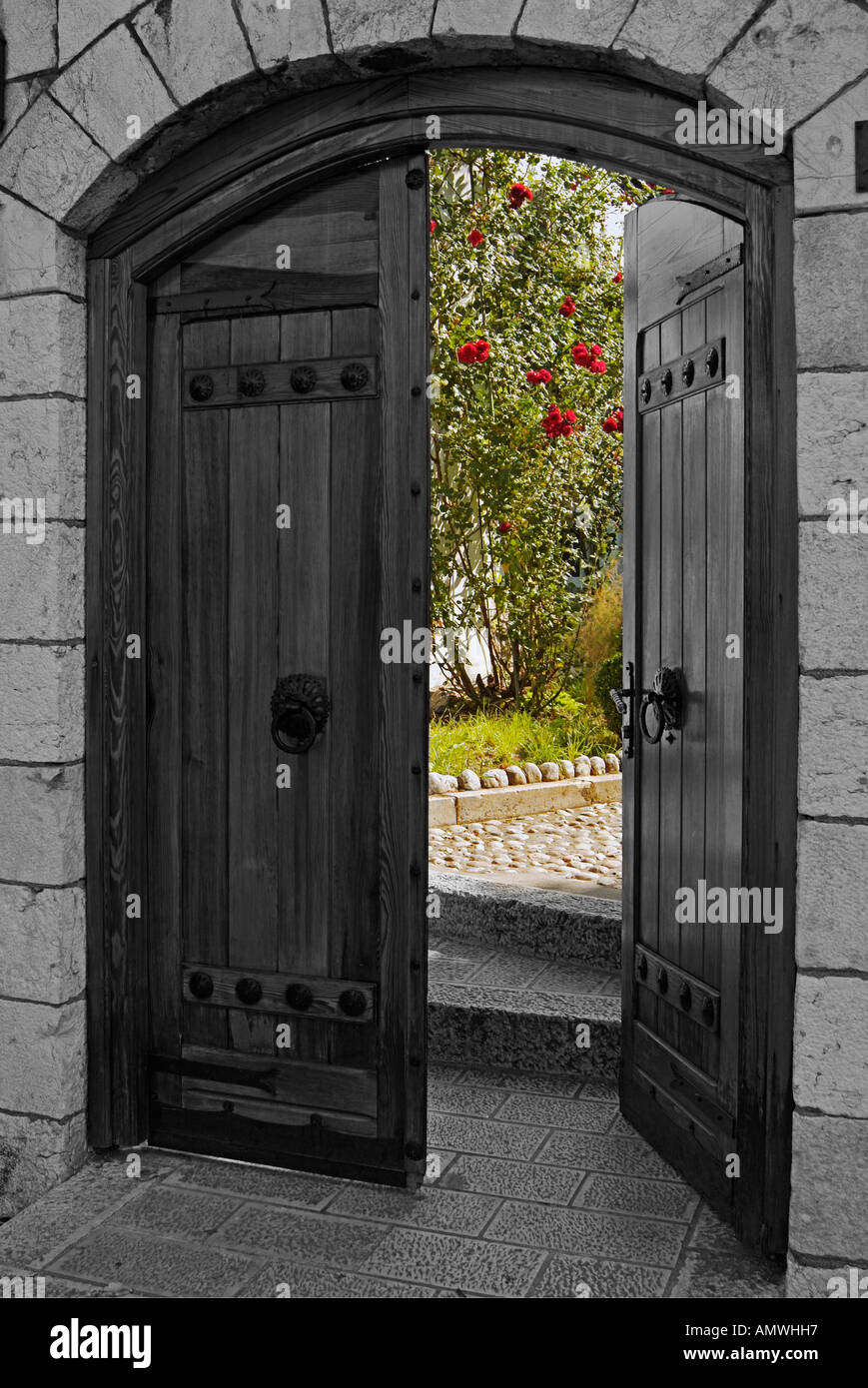 Gateway in un giardino di rose rosse che crescono fino a un muro Foto Stock