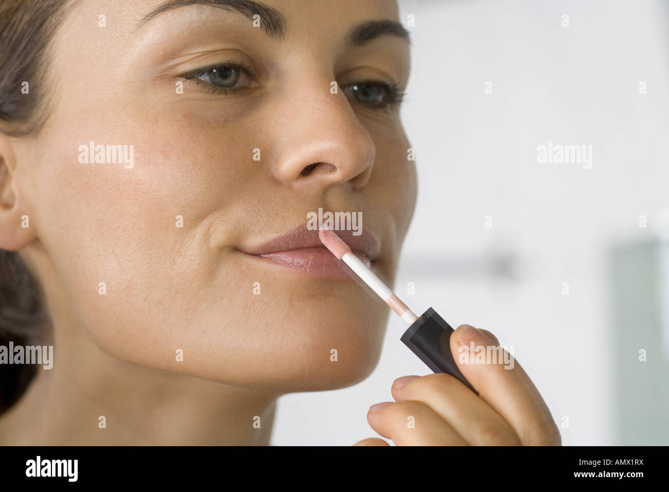 Giovane donna mettendo il rossetto di fronte a uno specchio Foto Stock