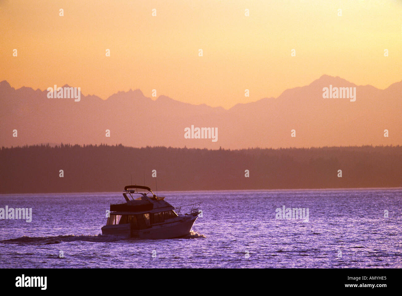 Power Boat su Elliott Bay con Bainbridge Island e la Olympic Mountain Range in background al tramonto Foto Stock