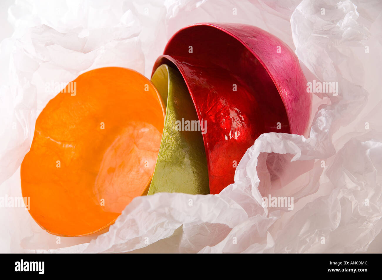 Set di cartapesta multi-colore di bocce, avvolto in carta velina bianca per un regalo. Girato su uno sfondo bianco. Foto Stock