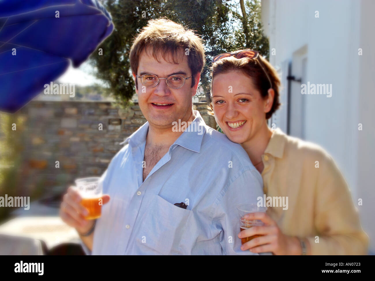 Giovane moglie tenendo teneramente il marito che è in possesso di un bicchiere di birra Foto Stock