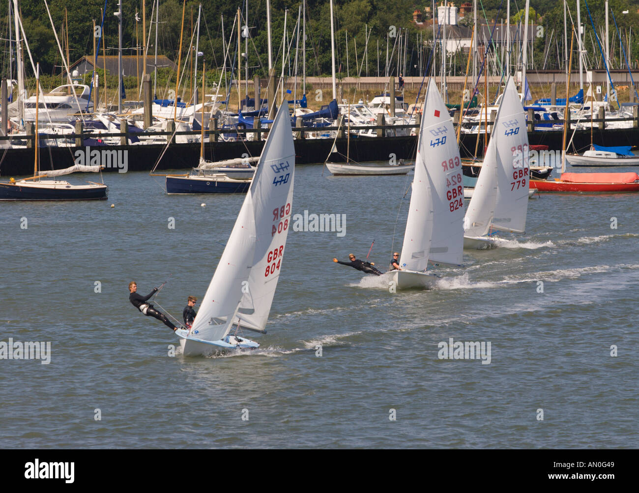 Trio di classe olimpica 470 due uomo racing derive a pieno la vela con montanti di yacht oltre a Lymington harbour Inghilterra Foto Stock