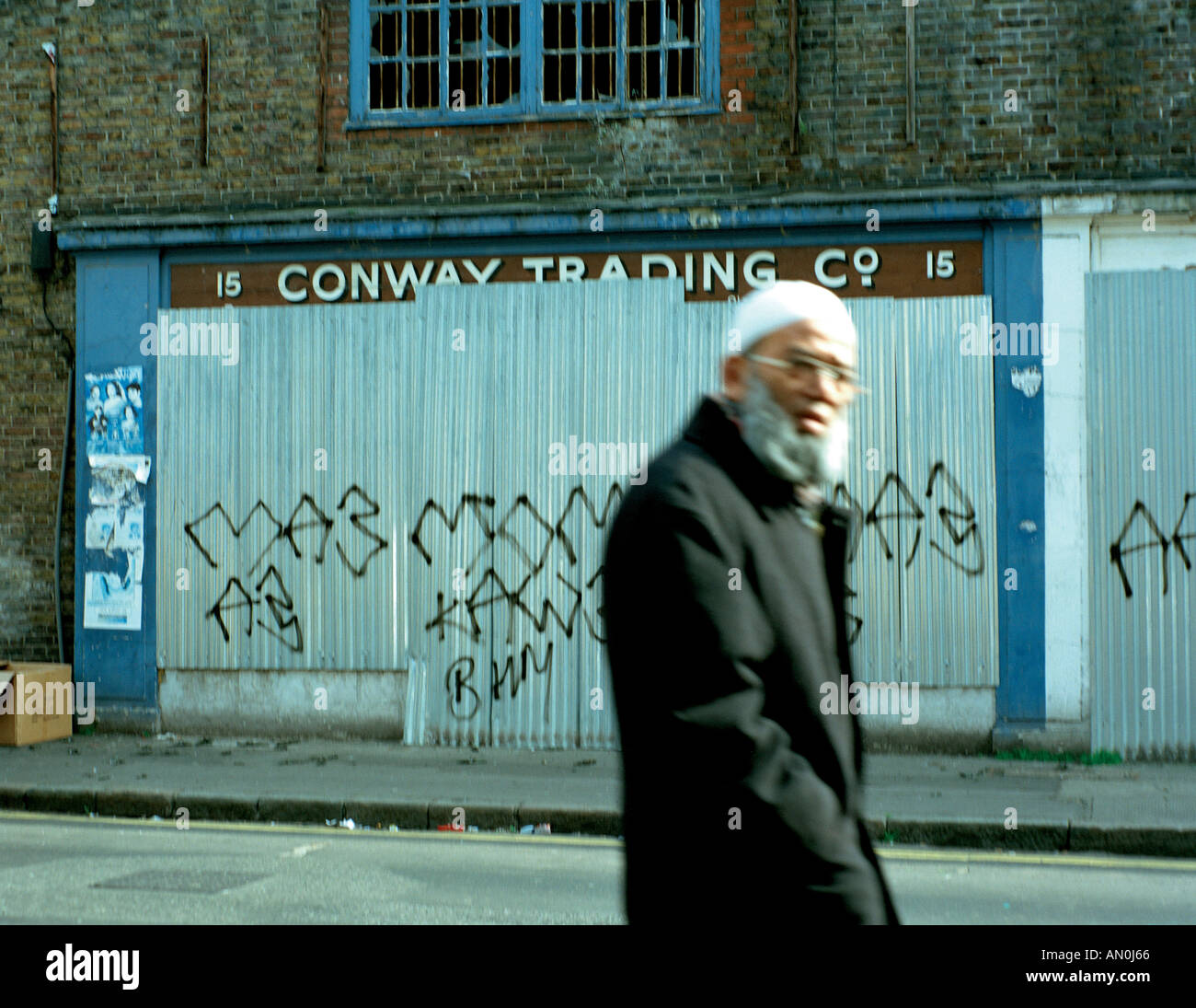 Anziani Bengali man walking passato edifici abbandonati in Aldgate East London Foto Stock