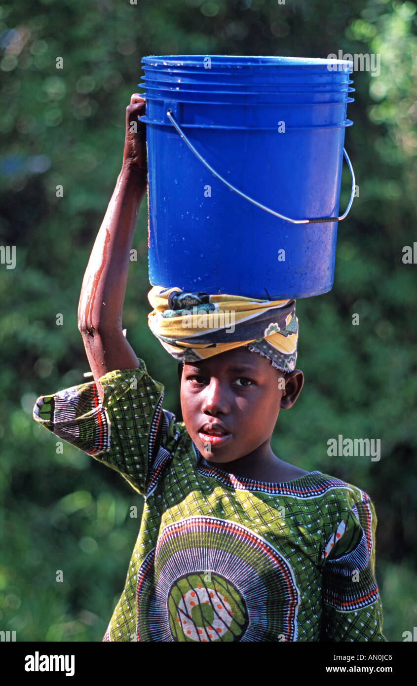 La ragazza da Utende con un secchio di acqua equilibrato sul suo capo mafia Mafia Island si trova tra Zanzibar e nord del Mozambico Foto Stock
